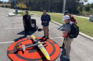 People operating a remote-control airplane on a target on the ground.