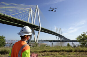 A TxDOT worker operating a drone beside a bridge. 